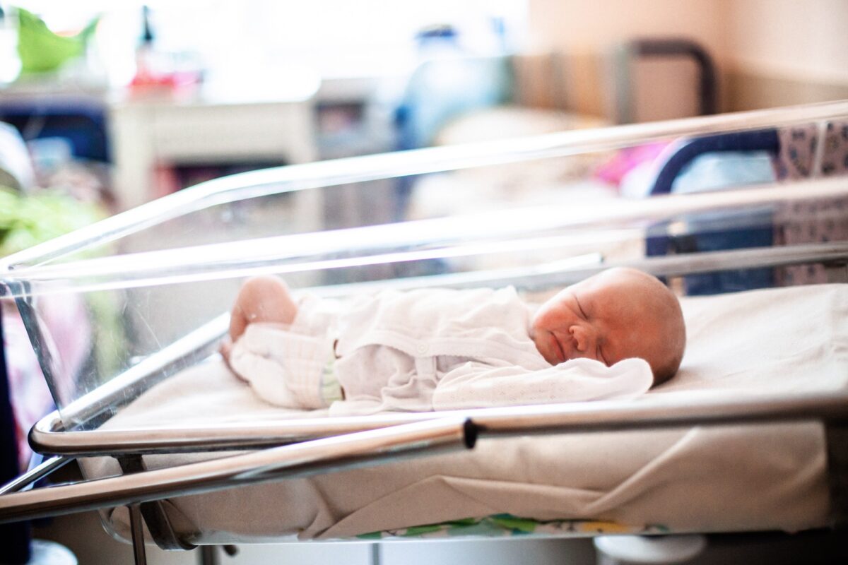 Close up of a newborn baby laying oh a bed in neonatal department of a hospital