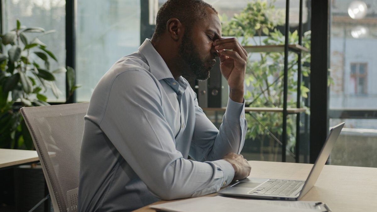 Exhausted sick mature senior businessman tired African American ethnic man office executive work on