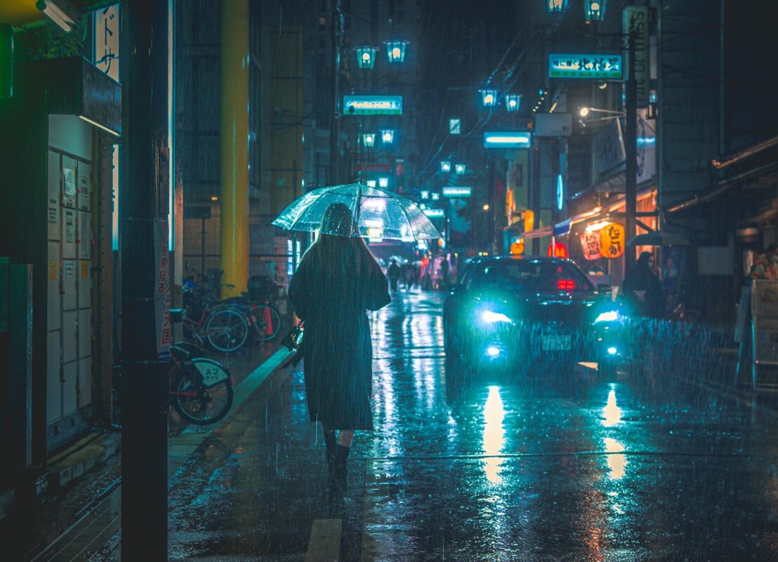 a person walking down a street in the rain with an umbrella