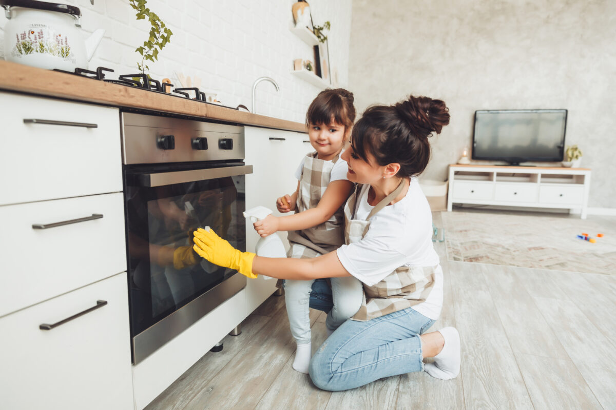 A little girl and her mother are cleaning the kitchen.