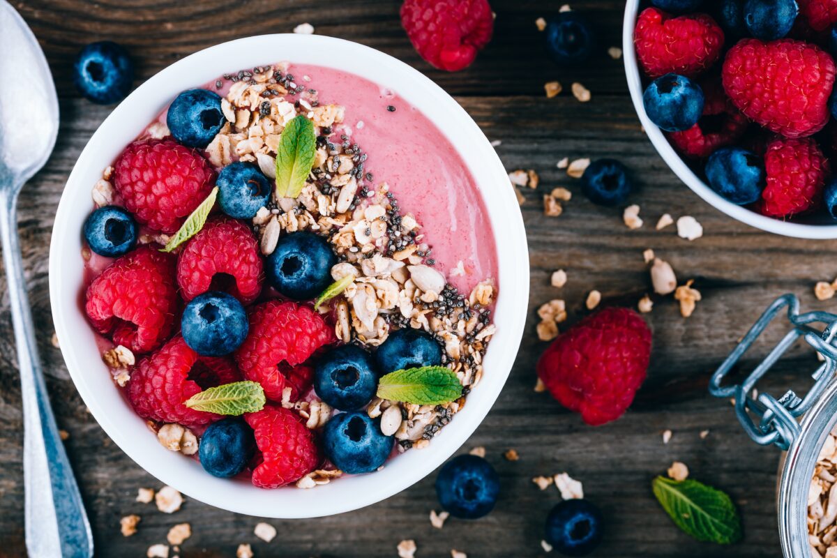 Acai smoothie and granola bowl with fresh raspberries and blueberries